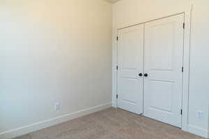 Unfurnished bedroom with light colored carpet and a closet