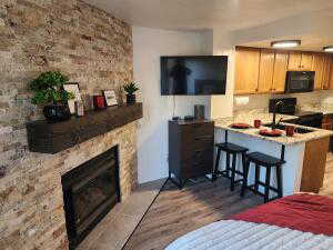 Kitchen with dark hardwood / wood-style flooring, a breakfast bar area, a fireplace, light brown cabinetry, and black appliances