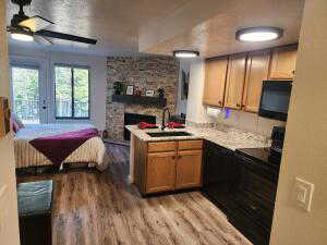 Kitchen with ceiling fan, sink, black appliances, and light hardwood / wood-style flooring