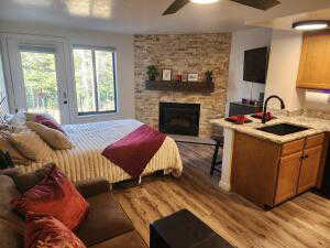 Great Room  featuring access to exterior, ceiling fan, sink, a fireplace, and light wood-type flooring