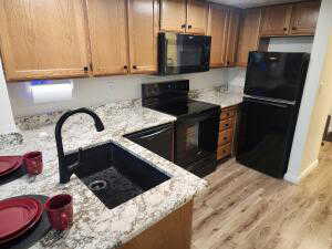 Kitchen featuring new stove, microwave and fridge. Black appliances, sink, light hardwood / wood-style flooring, light Granite counters, and kitchen peninsula