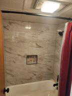 Bathroom with new tiled shower / tub combo with curtain