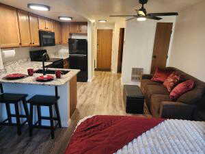 Kitchen with kitchen peninsula, a kitchen breakfast bar, ceiling fan, black appliances, and light hardwood / wood-style flooring