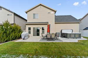 Back of property with a yard, a patio, and a hot tub