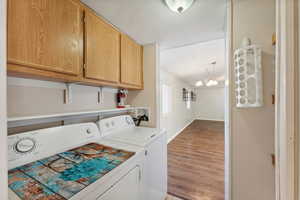 Washroom with cabinets, separate washer and dryer, a notable chandelier, wood-type flooring, and a textured ceiling