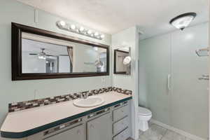 Bathroom with vanity, a textured ceiling, ceiling fan, tile patterned flooring, and toilet