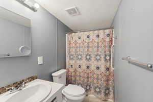 Bathroom with vanity, tile patterned flooring, toilet, a textured ceiling, and tasteful backsplash