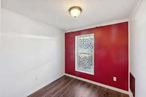 Empty room featuring dark hardwood / wood-style floors and ornamental molding