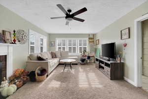 Living room with carpet, a textured ceiling, and ceiling fan