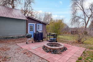 View of patio / terrace featuring an outbuilding, a fire pit, and a grill