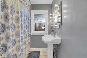 Bathroom featuring tile patterned floors, curtained shower, and sink