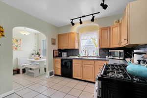 Kitchen featuring decorative backsplash, sink, stainless steel appliances, and light brown cabinetry