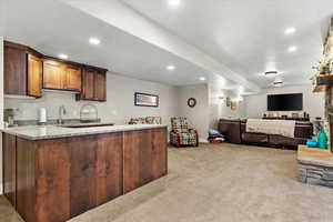 Kitchen with light carpet, kitchen peninsula, and light stone countertops