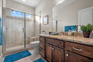 Bathroom with tile patterned flooring, vanity, toilet, and a shower with door