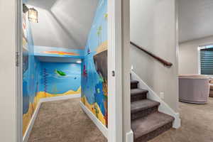 Stairs with carpet floors, a textured ceiling, and vaulted ceiling