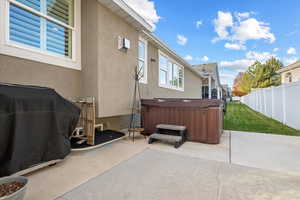 View of patio with area for grilling and a hot tub