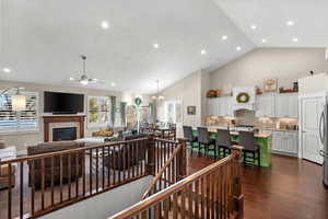 Living room featuring dark hardwood / wood-style floors, ceiling fan with notable chandelier, and vaulted ceiling