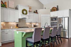 Kitchen featuring dark hardwood / wood-style flooring, white cabinetry, a kitchen island with sink, and appliances with stainless steel finishes