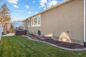 View of property exterior featuring a lawn, a patio area, a mountain view, and a hot tub