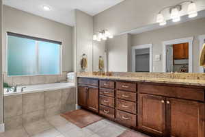 Bathroom featuring tile patterned flooring, vanity, and tiled tub