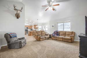 Living room with ceiling fan, light carpet, and lofted ceiling