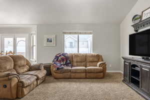 Living room featuring carpet flooring and vaulted ceiling