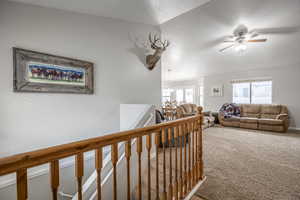 Hallway featuring carpet flooring, a chandelier, and lofted ceiling