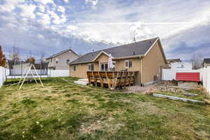 Back of property with a lawn, a trampoline, and a wooden deck