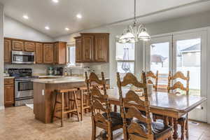 Dining room with a chandelier, light tile patterned floors, vaulted ceiling, and sink