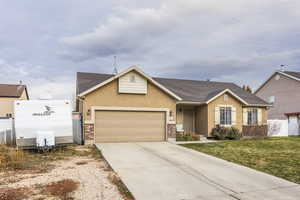 Single story home with a garage and a front lawn