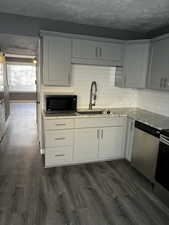 Kitchen featuring sink, dark hardwood / wood-style floors, a textured ceiling, appliances with stainless steel finishes, and white cabinetry