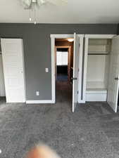 Unfurnished bedroom featuring ceiling fan and dark carpet