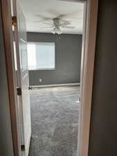 Carpeted spare room featuring ceiling fan