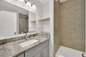 Bathroom with tiled shower / bath combo and vanity