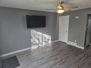 Empty room featuring hardwood / wood-style floors, a textured ceiling, and ceiling fan