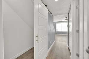 Corridor featuring a textured ceiling, light hardwood / wood-style floors, and a barn door