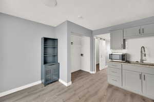 Kitchen featuring a barn door, backsplash, gray cabinets, light hardwood / wood-style floors, and sink