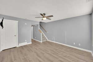 Unfurnished living room featuring ceiling fan, a barn door, and light hardwood / wood-style flooring