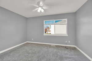 Carpeted empty room featuring ceiling fan