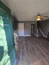 Unfurnished living room with a textured ceiling, ceiling fan, and dark wood-type flooring