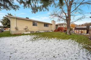 Rear view of property featuring a lawn, a storage shed, and a wooden deck