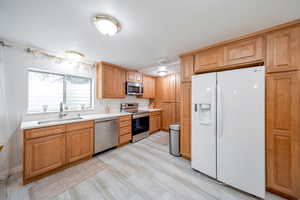 Kitchen with sink, lightwood-style flooring, and appliances with stainless steel finishes