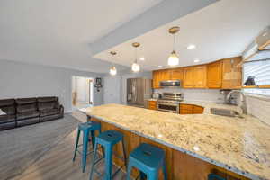 Kitchen featuring a breakfast bar area,  wood-style floors, decorative backsplash, and stainless steel appliances