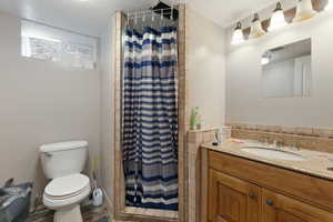 Bathroom with a shower with curtain, vanity, a textured ceiling, wood-type flooring, and toilet