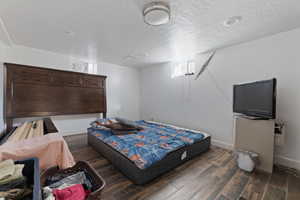 Bedroom with a textured ceiling and dark wood-type flooring