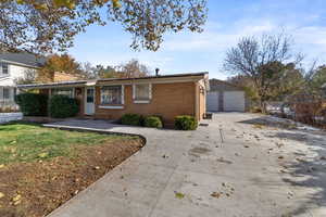 View of front facade featuring a garage, an outdoor structure, and a front yard