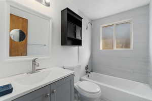 Full bathroom with vanity, tiled shower / bath combo, and toilet