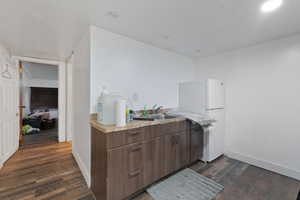 Kitchen featuring dark brown cabinets, dark hardwood / wood-style floors, white fridge, and sink