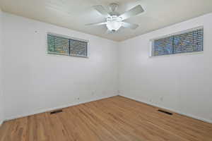 Spare room featuring wood-type flooring, ceiling fan, and a healthy amount of sunlight