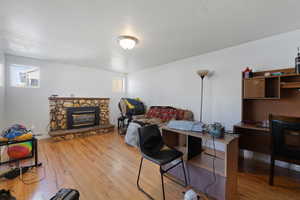 Bedroom with a stone fireplace and light hardwood / wood-style flooring